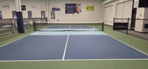 A clean blue and green indoor pickleball court with a JOOLA net at Rt. 12 Pickle in West Boylston, Massachusetts