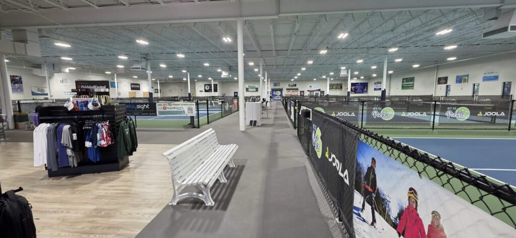 Inside Rt. 12 Pickle in West Boylston, Massachusetts, showing the pro shop and multiple indoor pickleball courts under a high warehouse ceiling