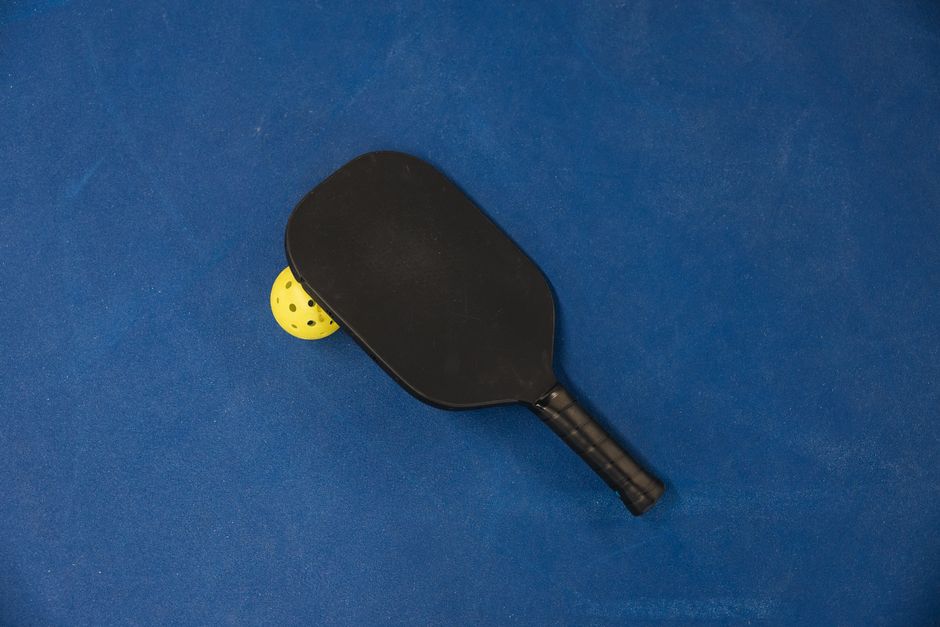 Pickleball paddle and ball on a court