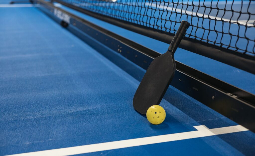 Pickleball in Stamford CT - paddle and ball at the net on an indoor court