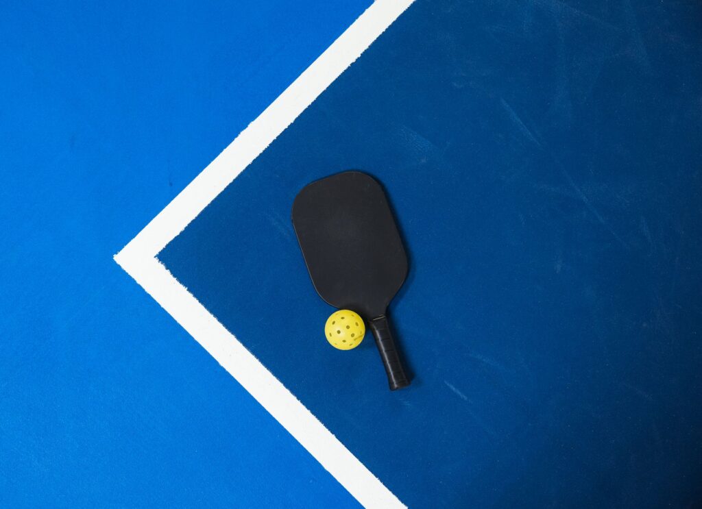 Pickleball paddle and ball on a blue court, illustrating USA Pickleball vision training for ball tracking