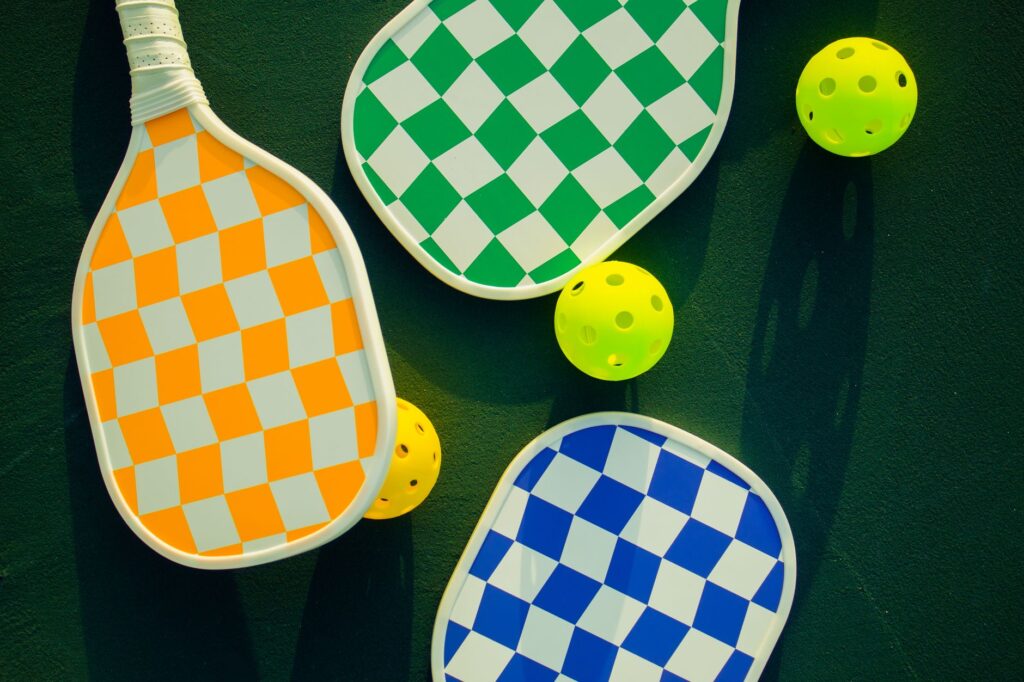Pickleball paddles and balls laid out on a sunny court - the best pickleball paddles for beginners in 2026