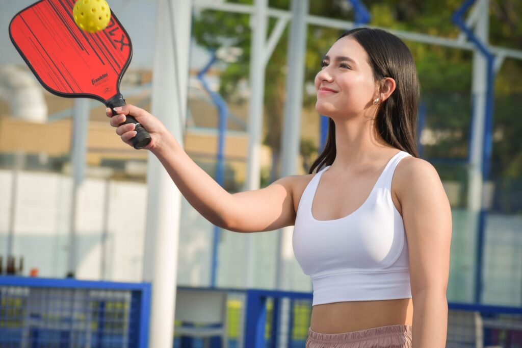 How to cover a lob in pickleball: player tracking a high ball with paddle raised