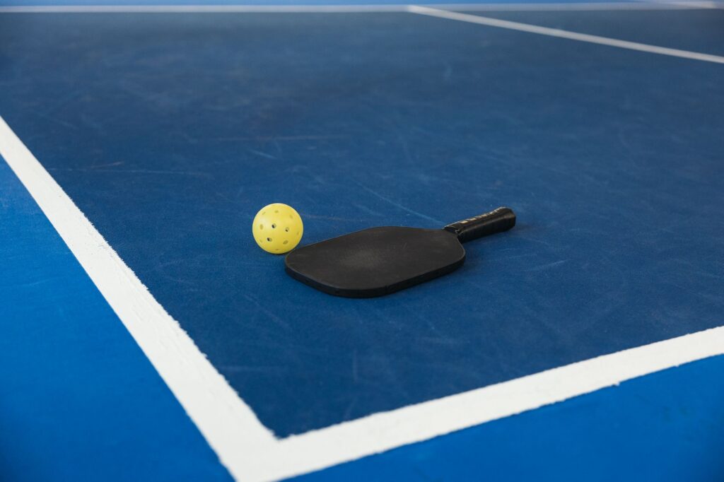 Pickleball paddle and ball beside the kitchen line where the kitchen bounce shot happens
