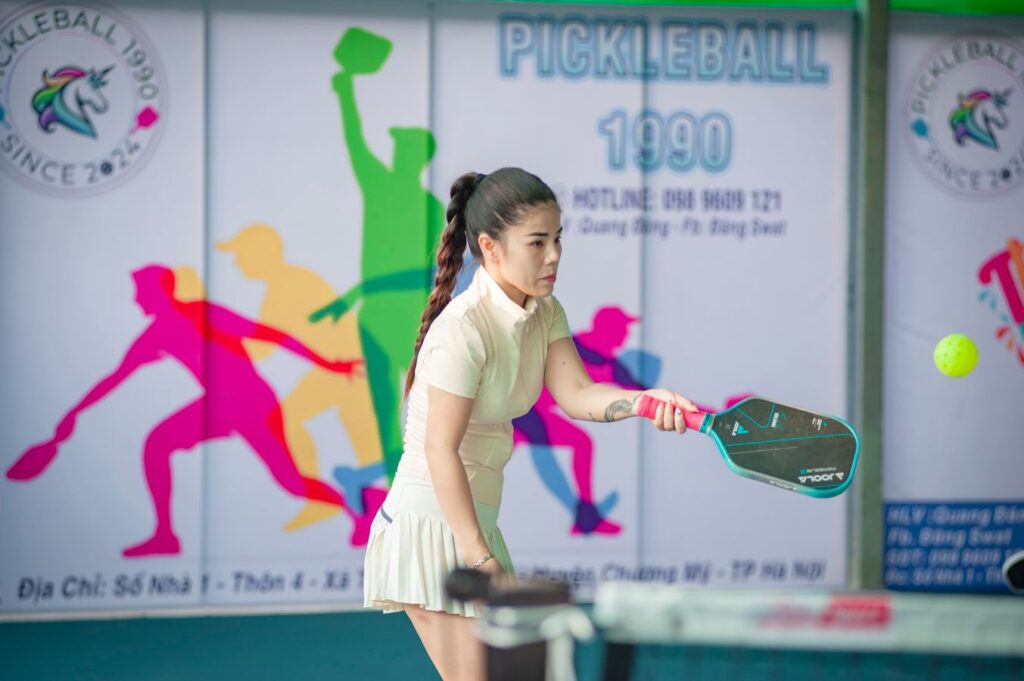 Pickleball player making contact out in front with a stable wrist, the technique that prevents a pop up dink