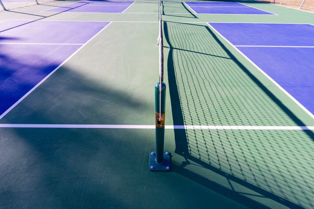 Blue and green outdoor pickleball court surface with permanent nets