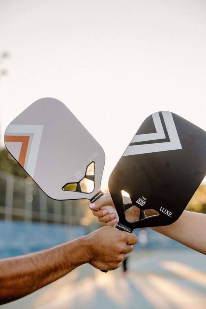 Expensive pickleball paddles compared: two pickleball paddles held side by side on an outdoor court
