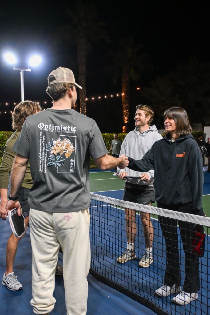 Pickleball players shaking hands across the net after a match, as pickleball facilities for sale are repriced across the country