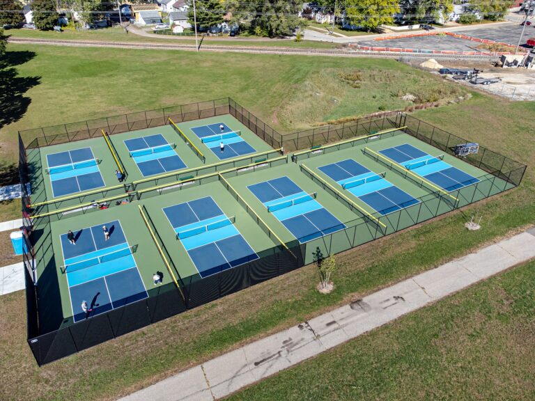 Aerial view of fenced public courts in a northern town park, the kind of outdoor setup for pickleball in Augusta ME