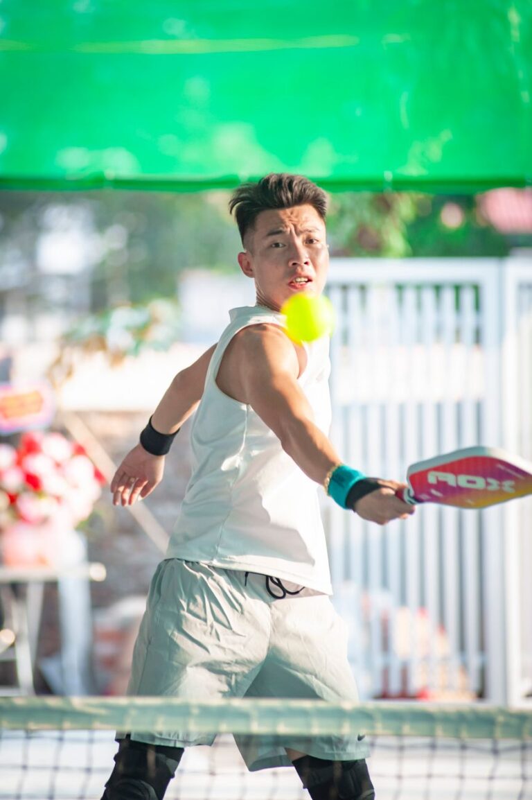 Player hitting a forehand at the net, the outdoor game behind pickleball in Guilford CT