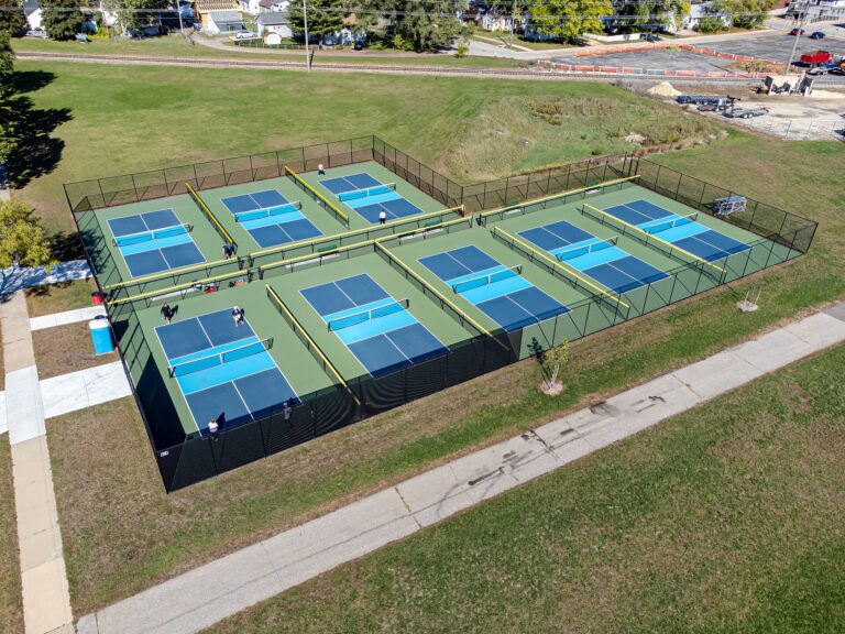 Aerial view of a fenced multi-court pickleball complex in a town park, similar in layout to pickleball in Meredith NH
