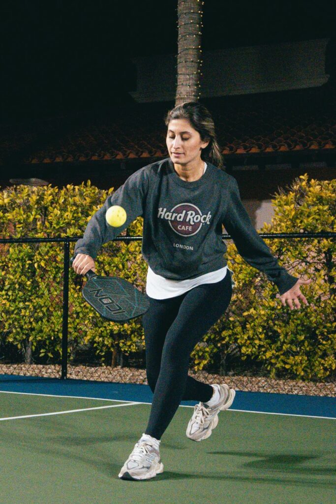 Scorpion shot in pickleball: a player dropping low with the paddle head below a rising ball at the kitchen line
