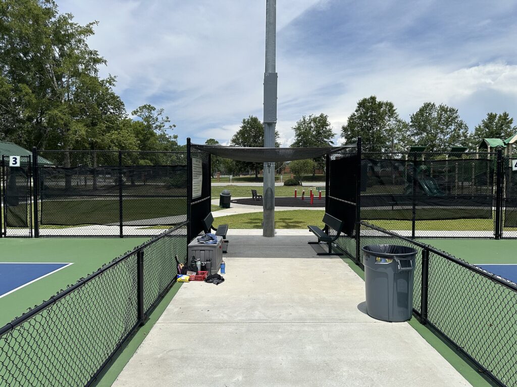 Windscreen-covered fencing between pickleball courts, relevant to Smithfield RI pickleball noise barriers