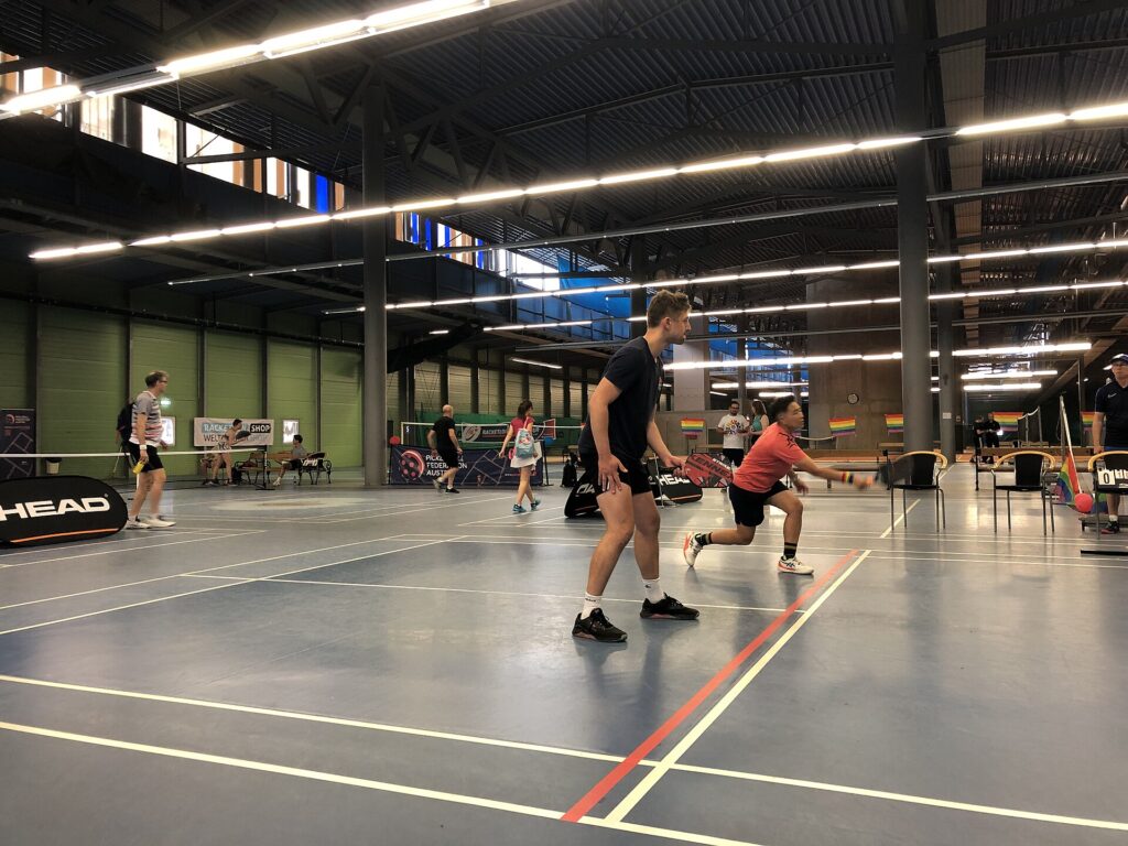 Players on several indoor pickleball courts in a large hall, the setup behind the best pickleball clubs in New England