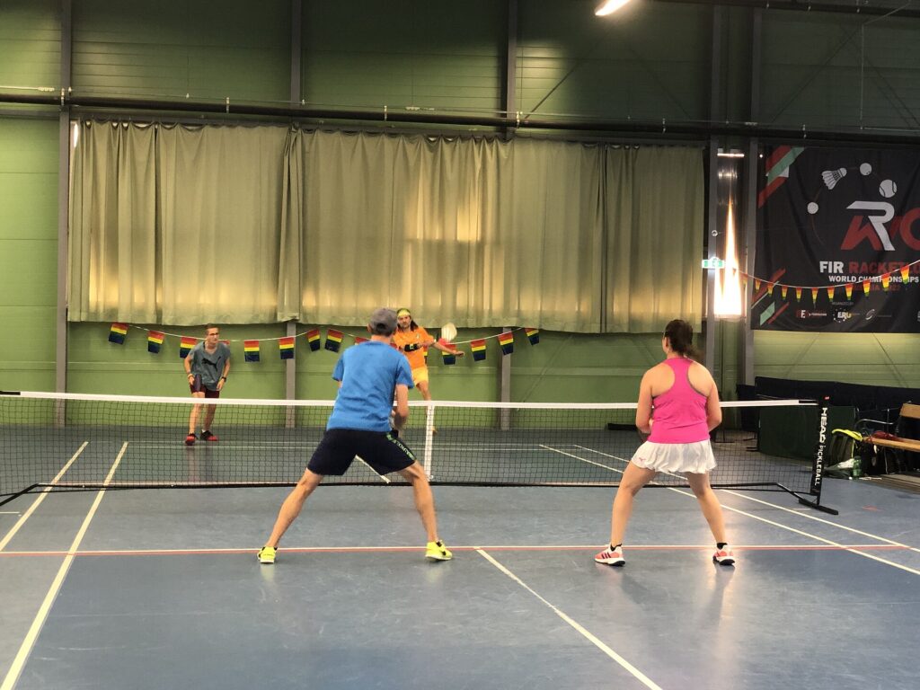 Doubles players set at the kitchen line as an opponent attacks, illustrating body shots in pickleball