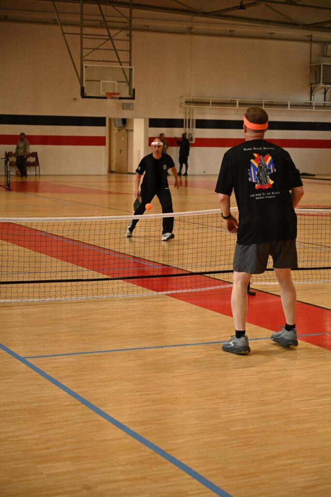 Indoor gym rally with paddle and ball in view, for our elongated vs widebody pickleball paddle comparison