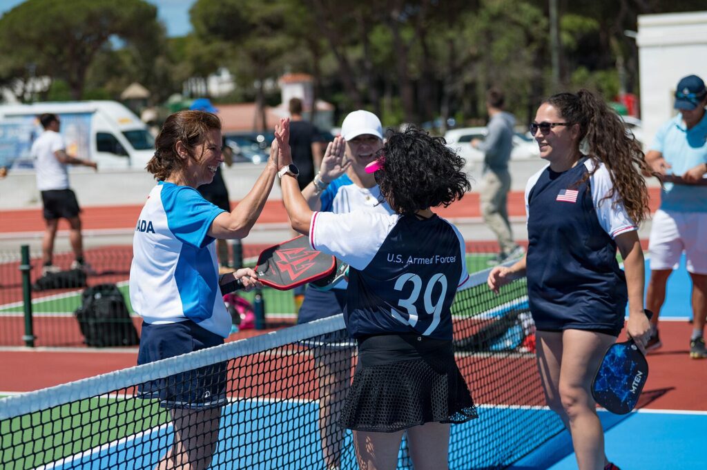 Pickleball players high-fiving across the net after a doubles match, the public play planned for the Hingham pickleball courts
