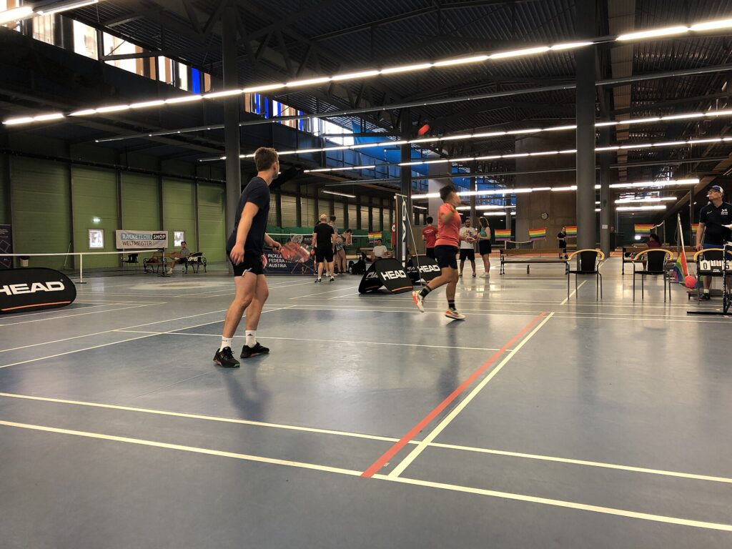 Indoor doubles match in an arena hall, like the Hong Kong Slam courts at Kai Tak Arena