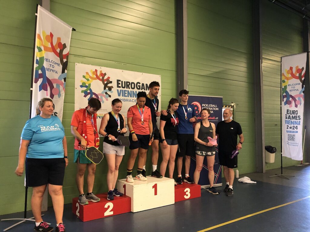 Medal winners on a tournament podium, the first rung on how to become a pro pickleball player
