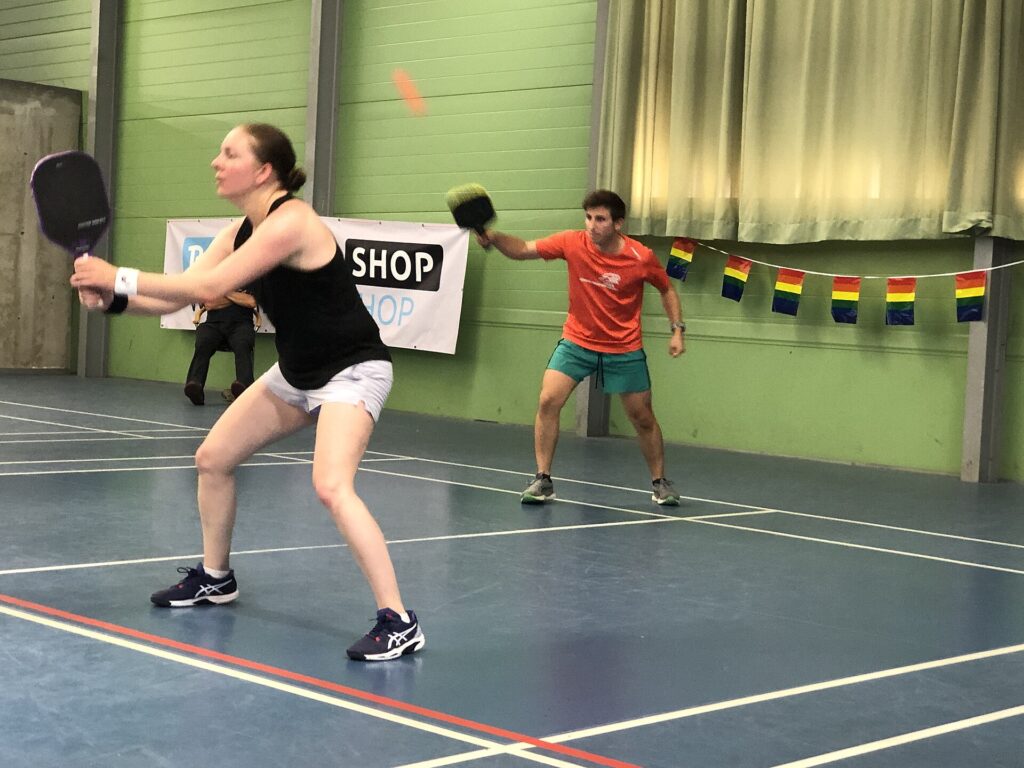 Indoor pickleball doubles players hitting a dink in a gym, the winter option once Williston pickleball courts close