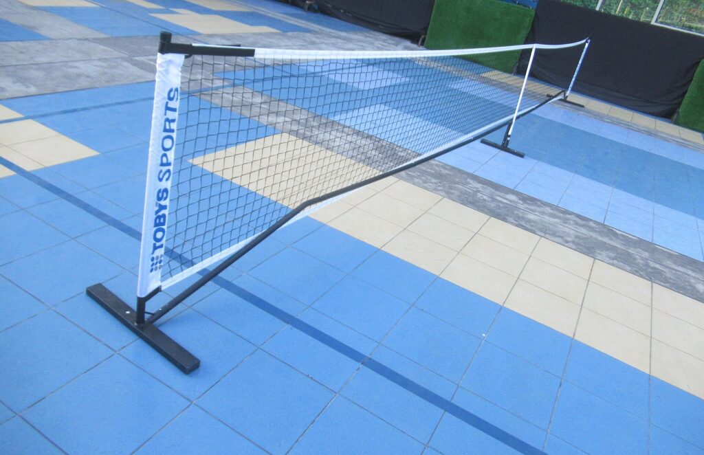 Portable pickleball net set up on a blue sport-tile court