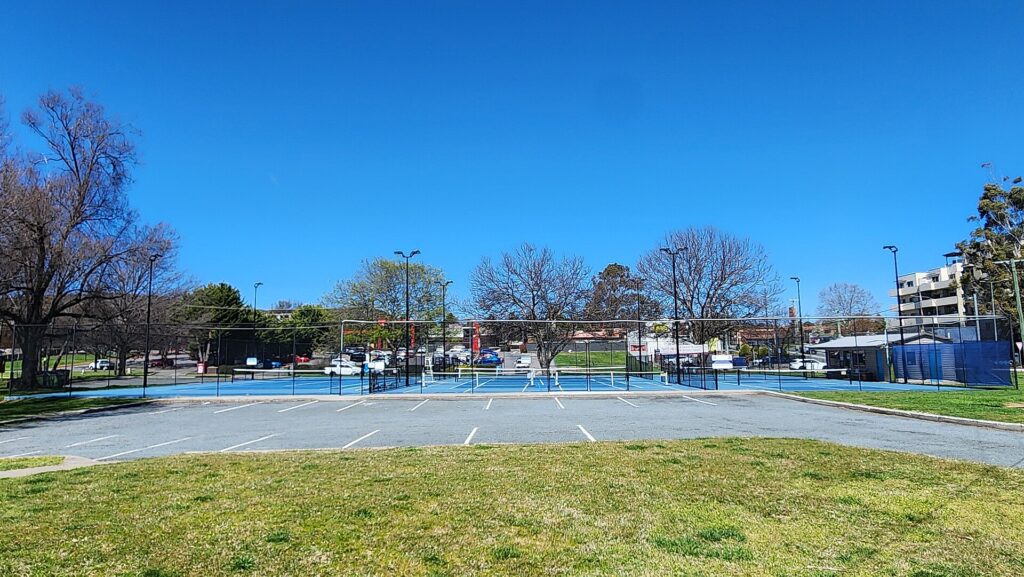 Fenced public tennis and pickleball courts in a town park, like the shared courts for pickleball in Warren