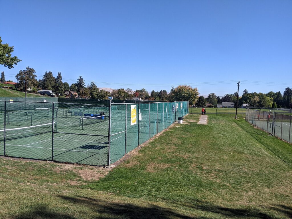 Pickleball nets set up on fenced town tennis courts beside a park, a common setup for pickleball in Bloomfield and other Connecticut towns