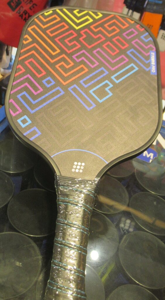 A pickleball paddle with a wrapped grip, showing the handle length below the hitting face