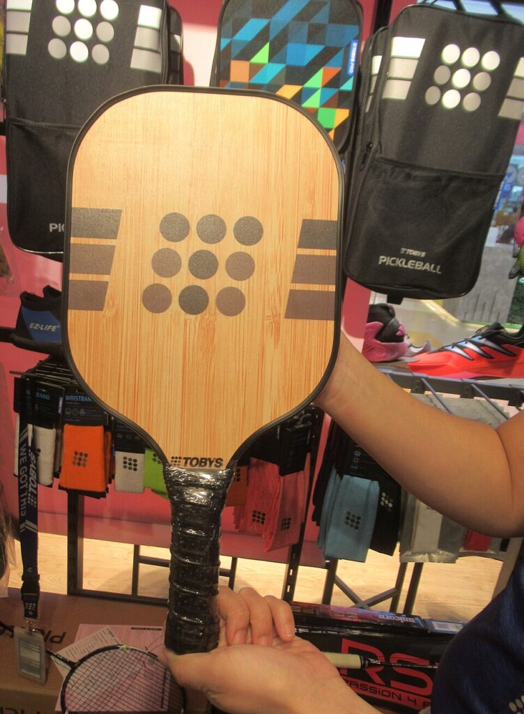 A hand holding a pickleball paddle by its handle, showing pickleball paddle handle length against the face