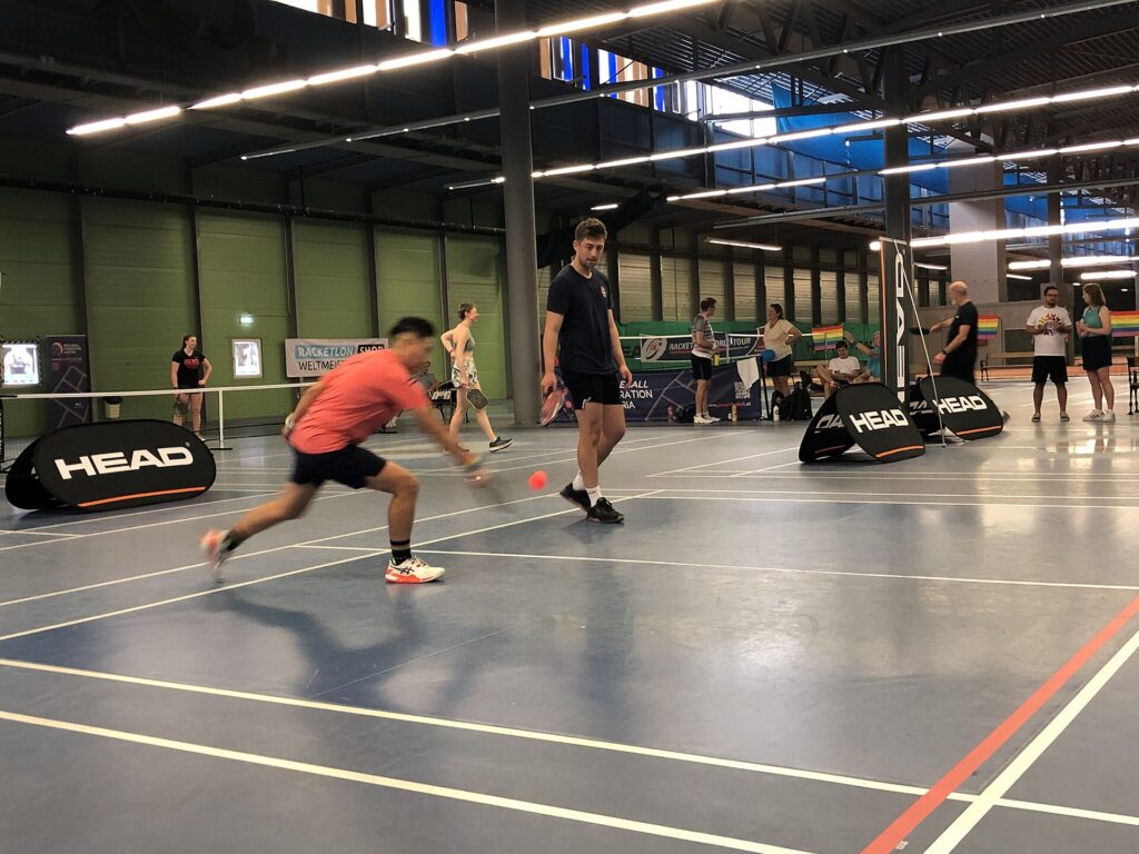 A pickleball player lunging for a low ball during a tournament doubles point